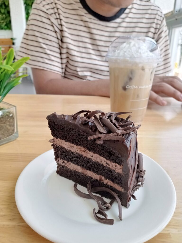 An image of a man enjoying a cup of coffee and a slice of triple chocolate cake.