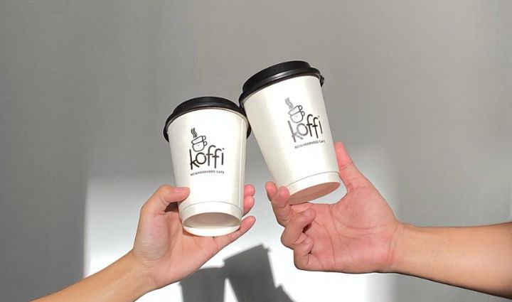 An image of two hands holding a takeaway cups of.