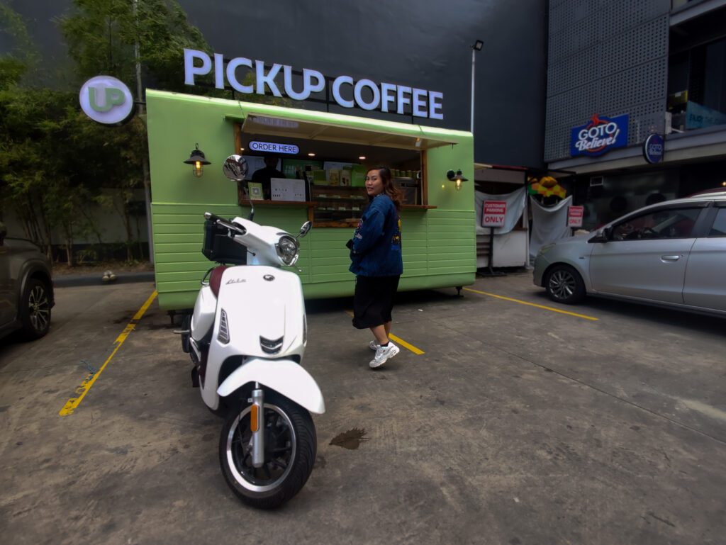 a girl buying pickup coffee with vintage style white motorcycle 