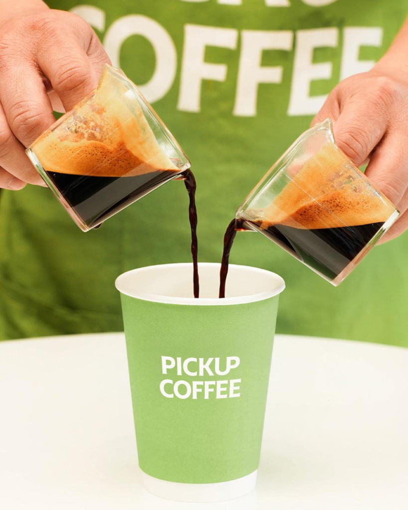 two shots of espresso pouring over the cup of pickup coffee.